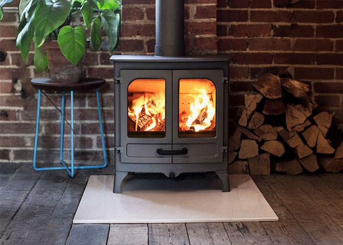 An Island II Charnwood Stove with logs burning inside.